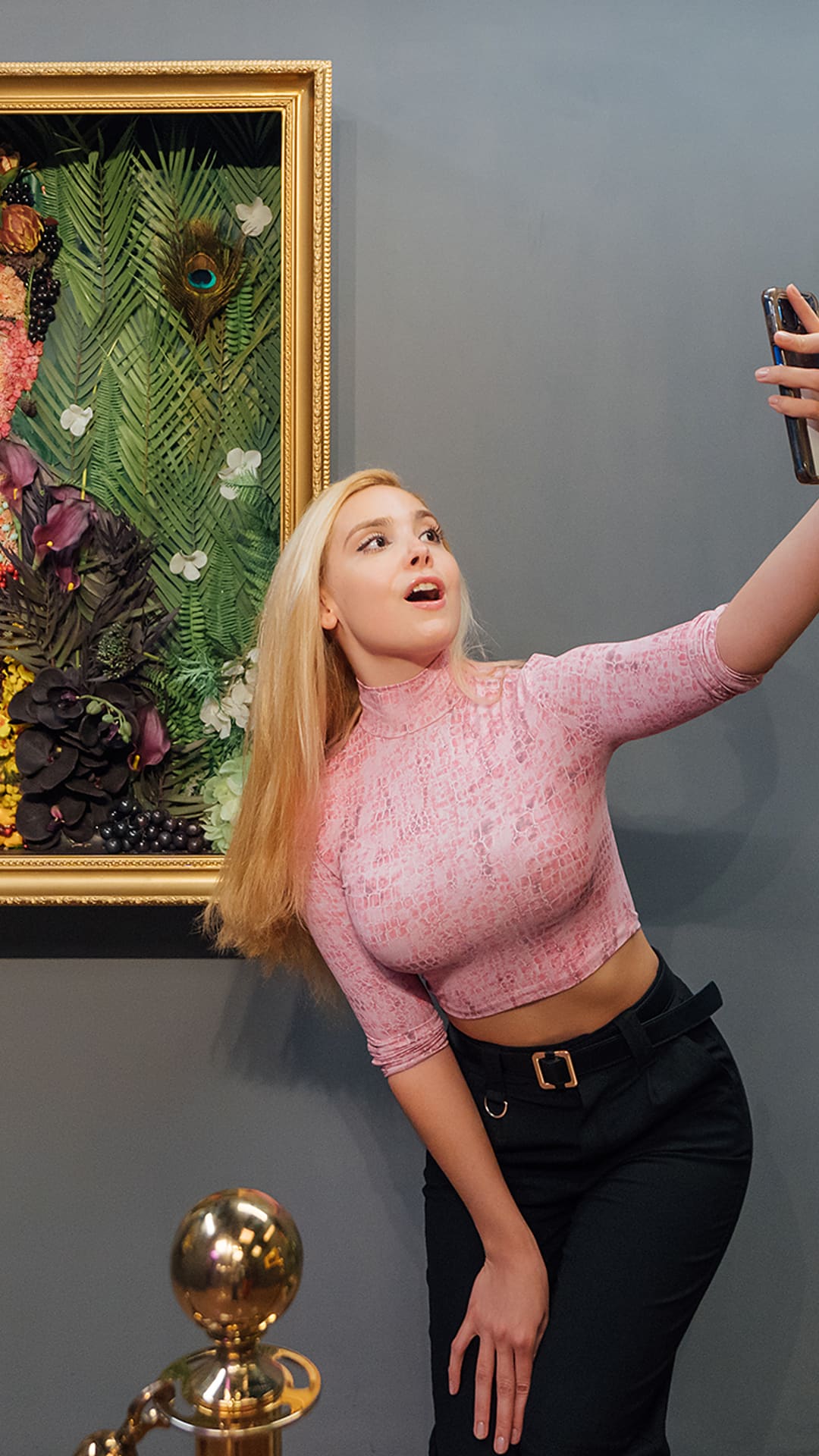 Visitor taking a selfie beside a Frida Kahlo portrait recreated entirely from flowers and fruit at Food Art Museum Barcelona